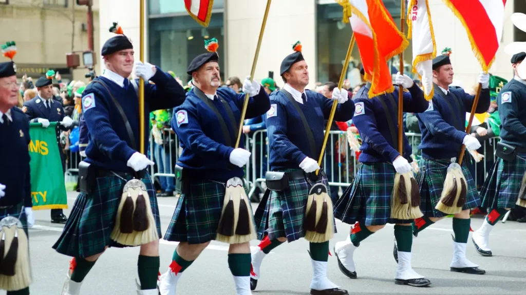 Performers wearing green costumes marching in a St. Patrick’s Day parade.
